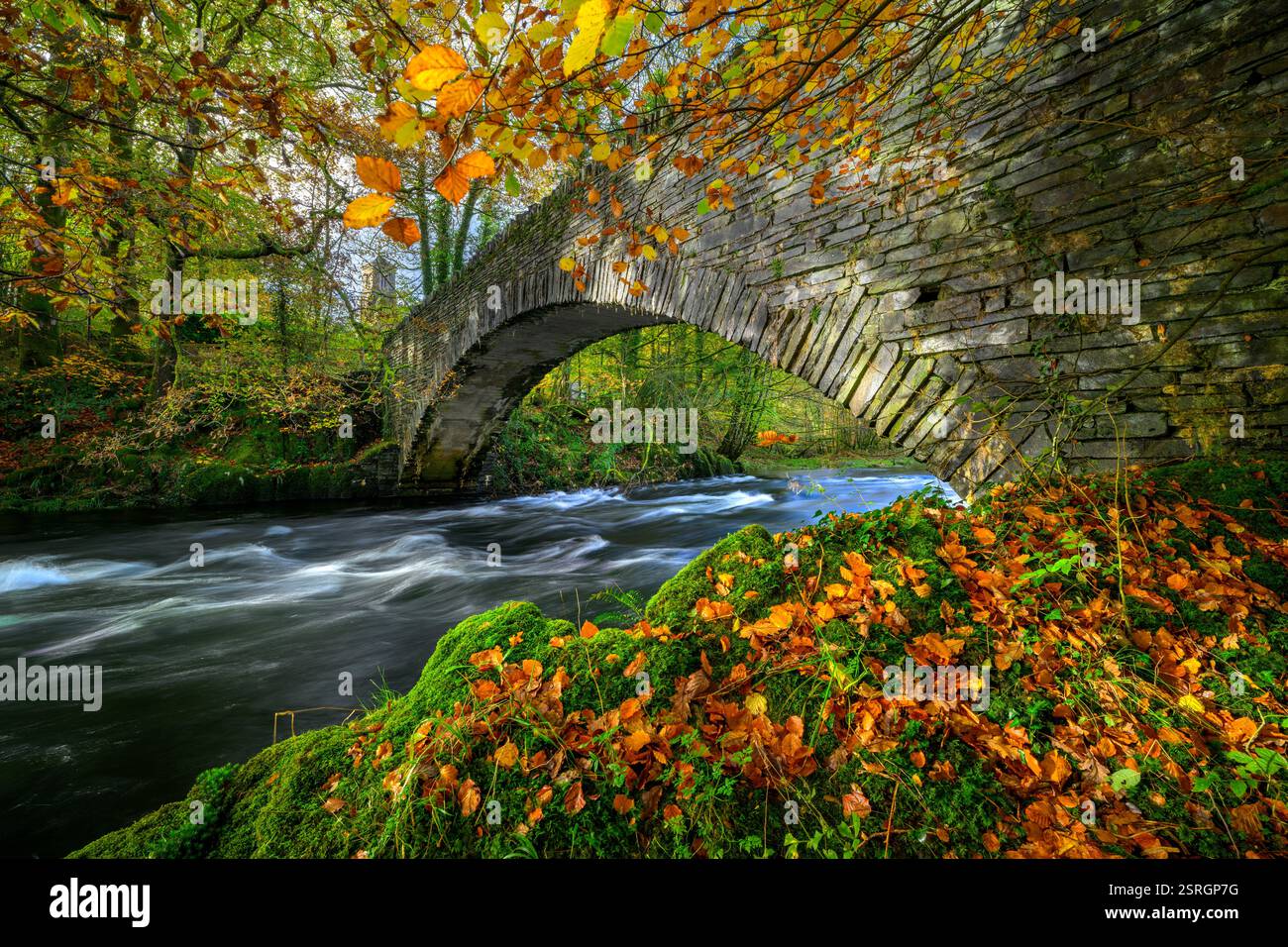 Lake District colora l'autunno al ponte a cavallo di Clappersgate con sullo sfondo la chiesa della Santissima Trinità di Brathay. Foto Stock
