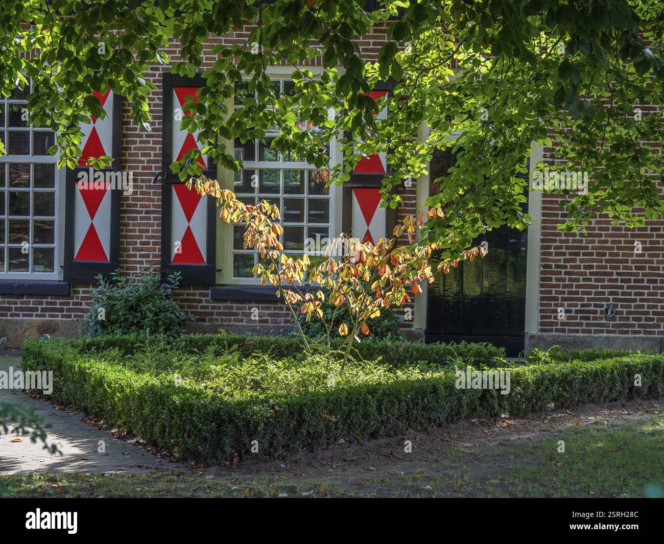 Giardino di fronte a una casa con persiane accattivanti e alberi frondosi, losser, Paesi Bassi Foto Stock