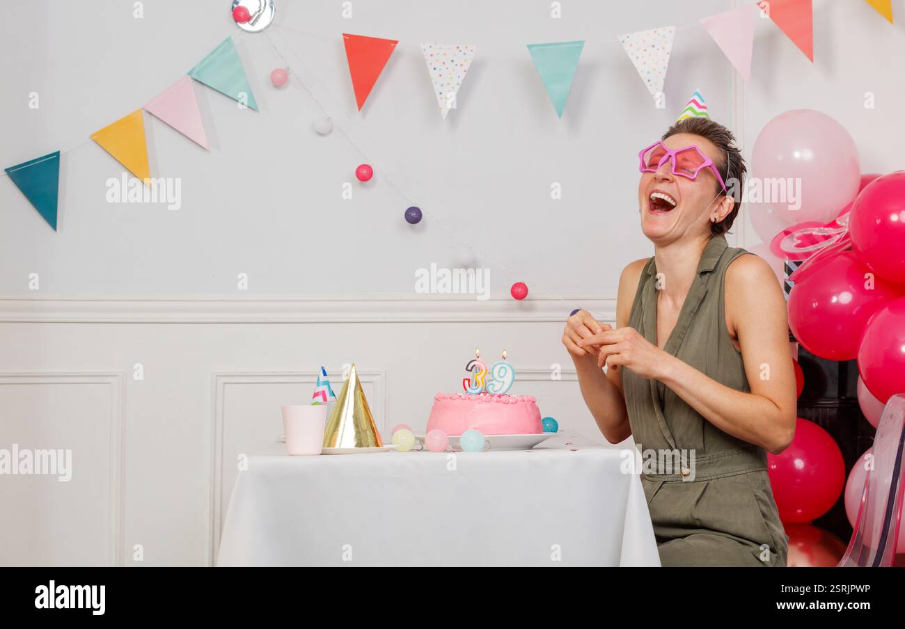 La donna festeggia il 39° compleanno con decorazioni e gioia Foto Stock