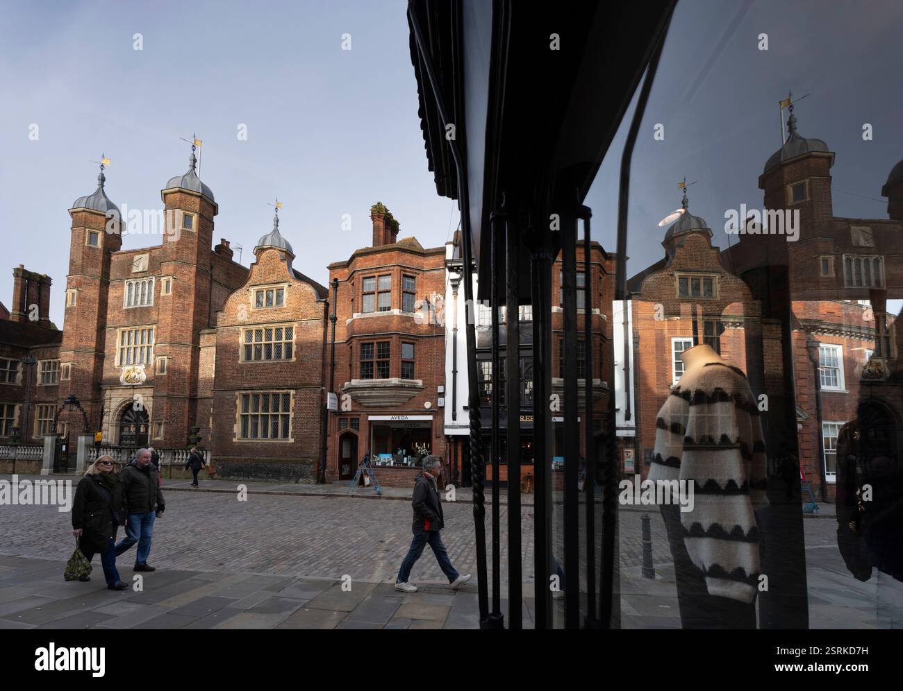 I pedoni passano davanti alla storica Guildford, riflessa in una vetrina. Foto Stock