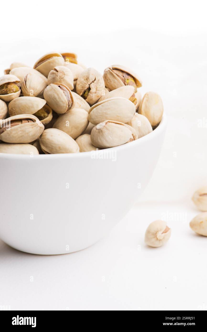 Ciotola di pistacchi arrostiti su sfondo bianco Foto Stock