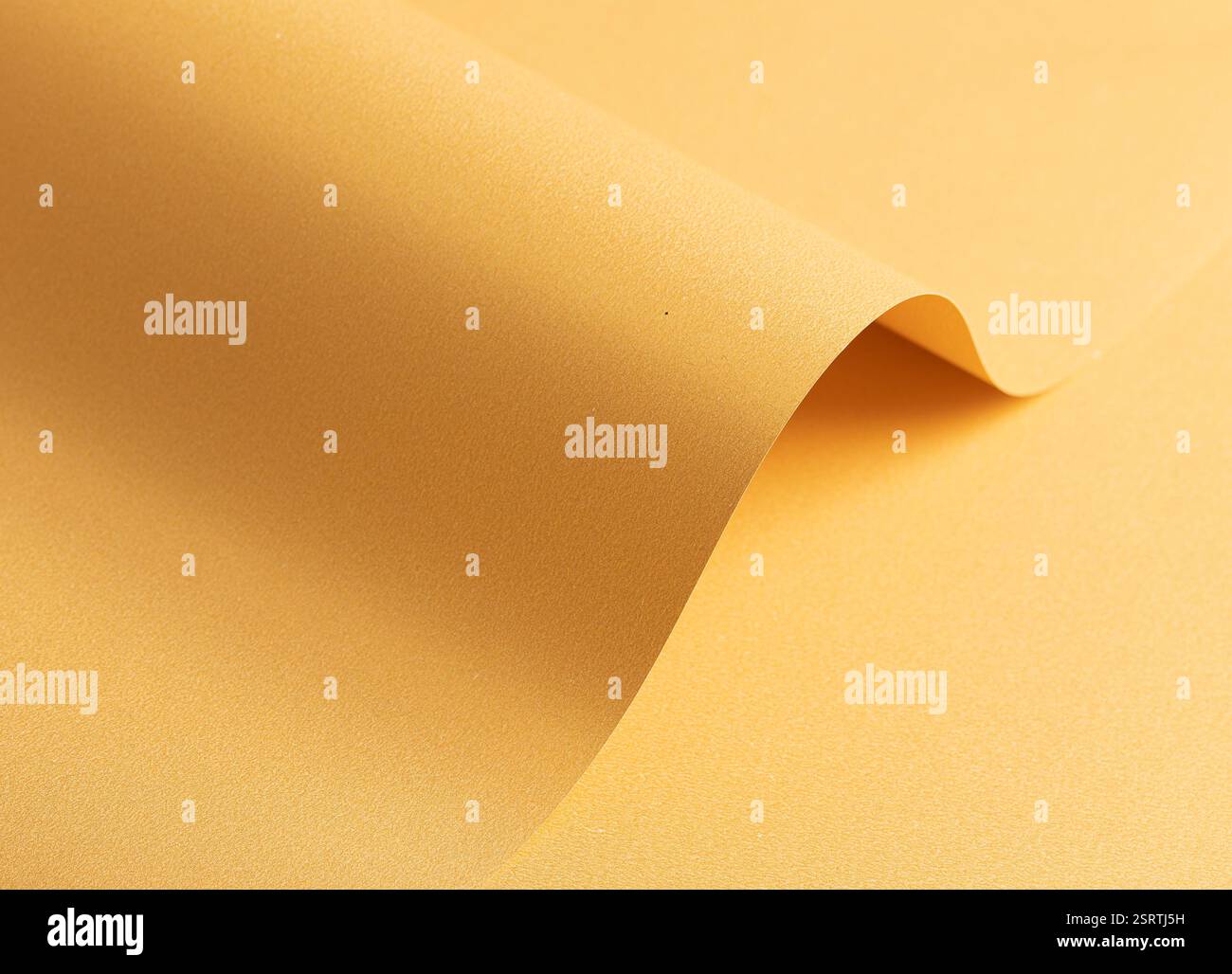 Sfondo in carta giallo dorato con una trama uniforme e curve sottili. Sfumature morbide e ombre raffinate creano un ambiente elegante, sofisticato e harmo Foto Stock
