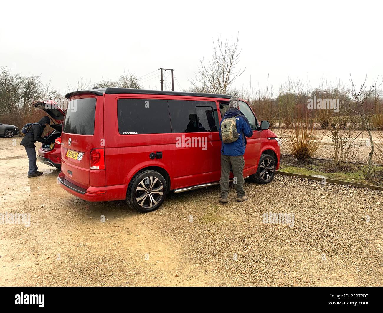 Red VW Volkswagen van bus luminoso camper per per le vacanze finestrini elettrici color ciliegio vetro colorato paraurti grigi manici finitura nera accampamento - Immagine stock catturata con smartphone