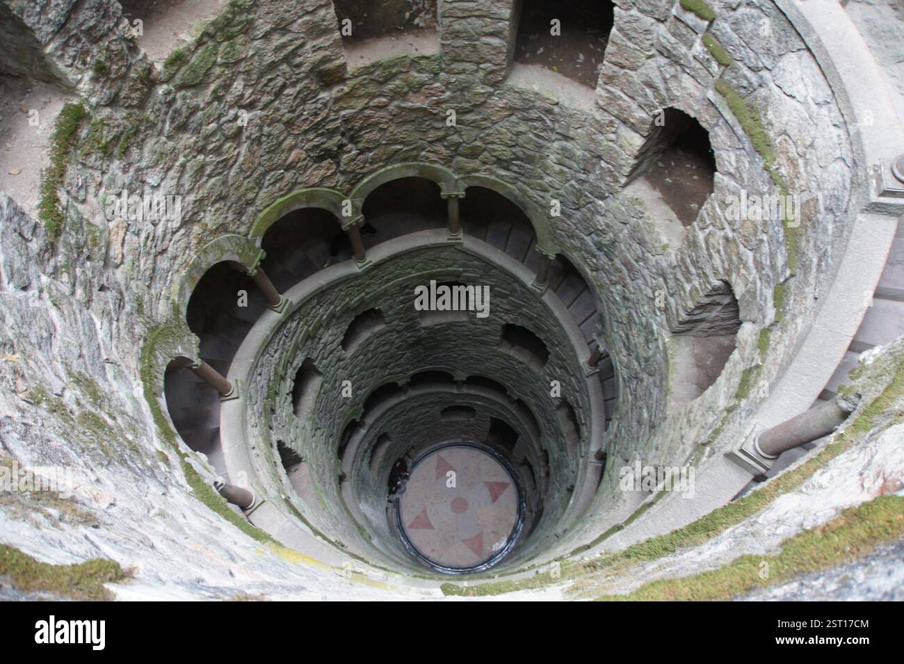 Una tortuosa scala a chiocciola in pietra scende in un interno scuro e ben simile. Sintra, Portogallo. L'atmosfera misteriosa e quasi ritualistica pervade la Foto Stock