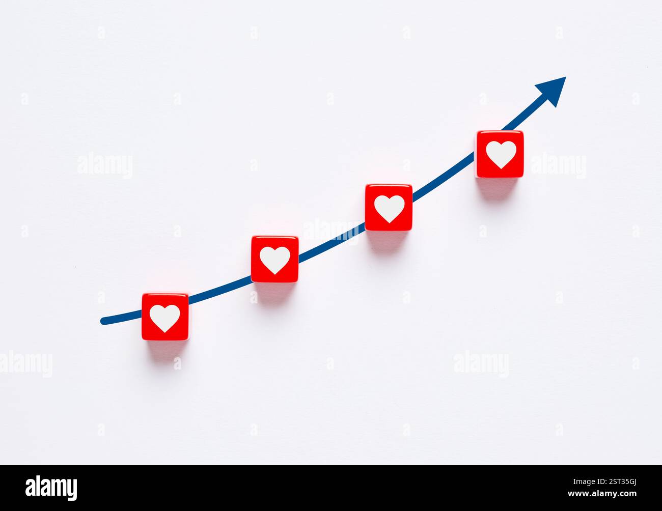 Il grafico a linee è in aumento e mostra cubi rossi con un cuore bianco. L'amore e la relazione romantica stanno diventando piu' forti. Aumentare l'amore e l'intimità. In crescita Foto Stock