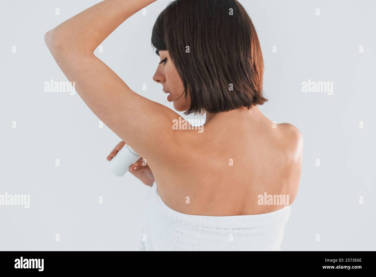 Con deodorante a sfera. La giovane bruna è all'interno su sfondo bianco. Foto Stock