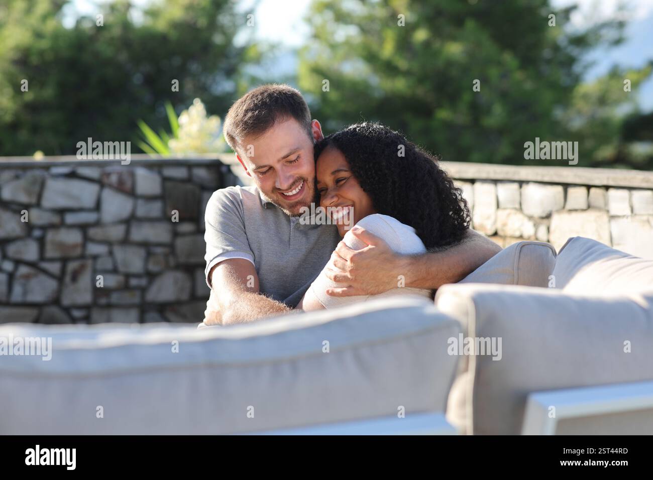 Felice coppia interrazziale che abbraccia in terrazza una giornata di sole Foto Stock