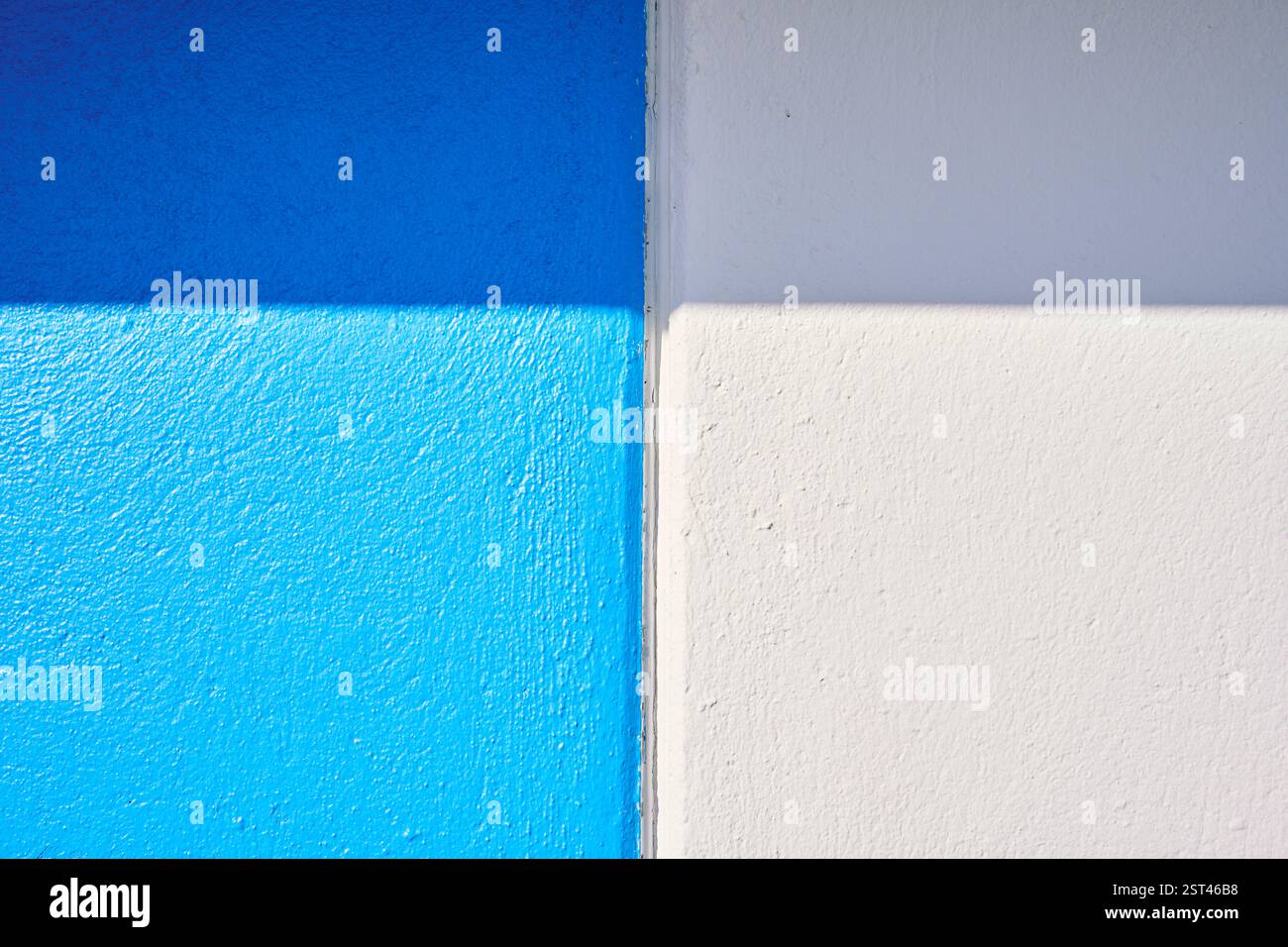 Luce solare che crea ombra su pareti blu e bianche Foto Stock