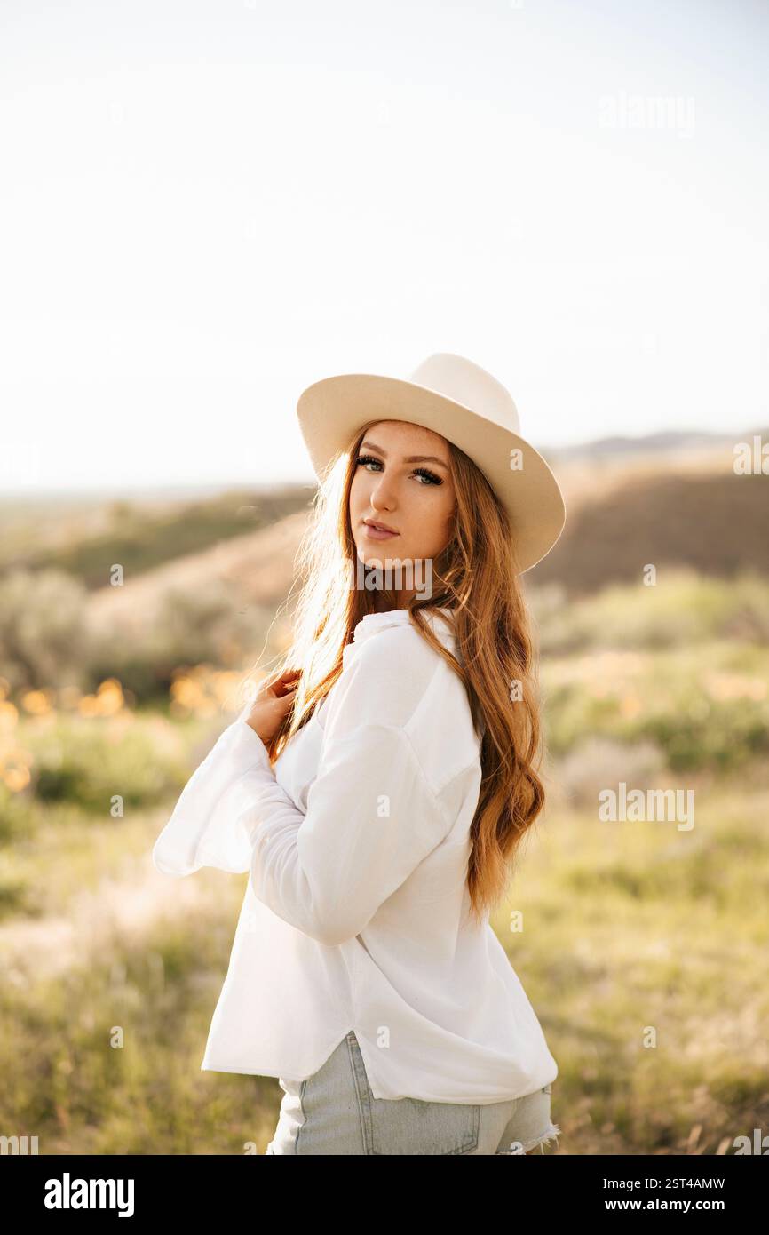 Una giovane donna brillante con una camicia e un cappello bianchi Foto Stock