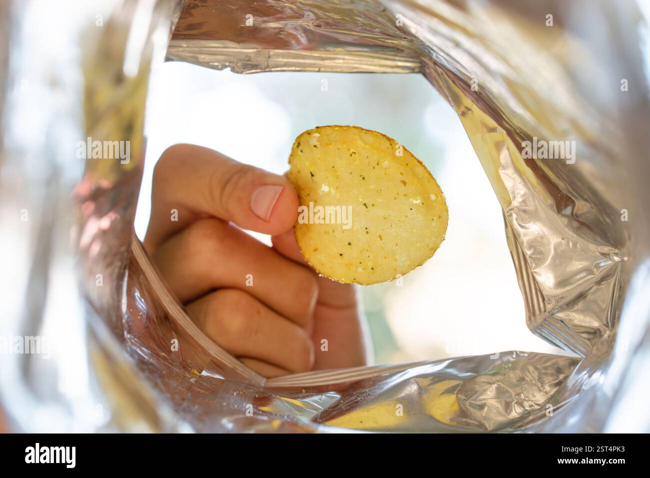 Raccogliere a mano le patatine all'interno del sacchetto. Un pacchetto aperto di patatine. vista della confezione interna Foto Stock