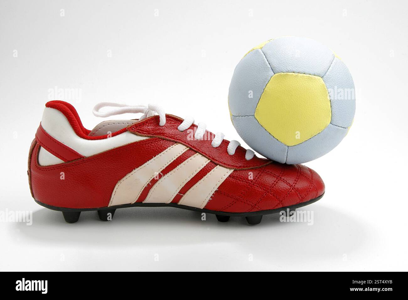 Scarpa rossa e palla in pelle blu e gialla di calcio o sport calcistico Foto Stock
