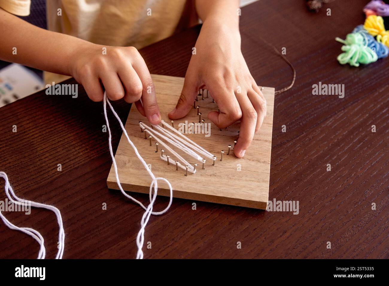 Le piccole mani intrecciano il cordoncino intorno alle unghie, creando uno splendido design. Un mix di pazienza, apprendimento e divertimento. Foto Stock