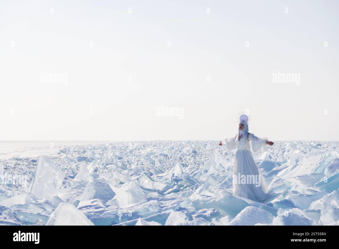 Ice Queen in un vestito bianco seduto su schegge ghiacciate al lago Baikal. Incantevole ambientazione da favola invernale Foto Stock