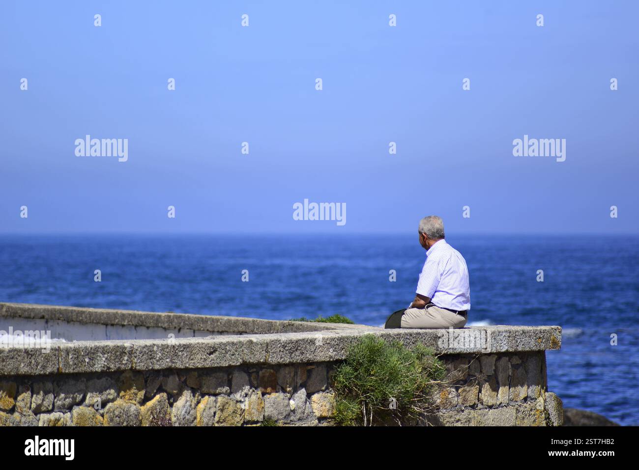 Un uomo anziano seduto davanti all'oceano in un giorno di primavera Foto Stock