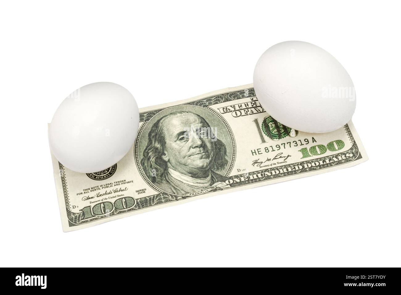 Colpo orizzontale di due uova di pollo bianche sedute su una banconota da cento dollari isolata su bianco con spazio per copiare. Foto Stock