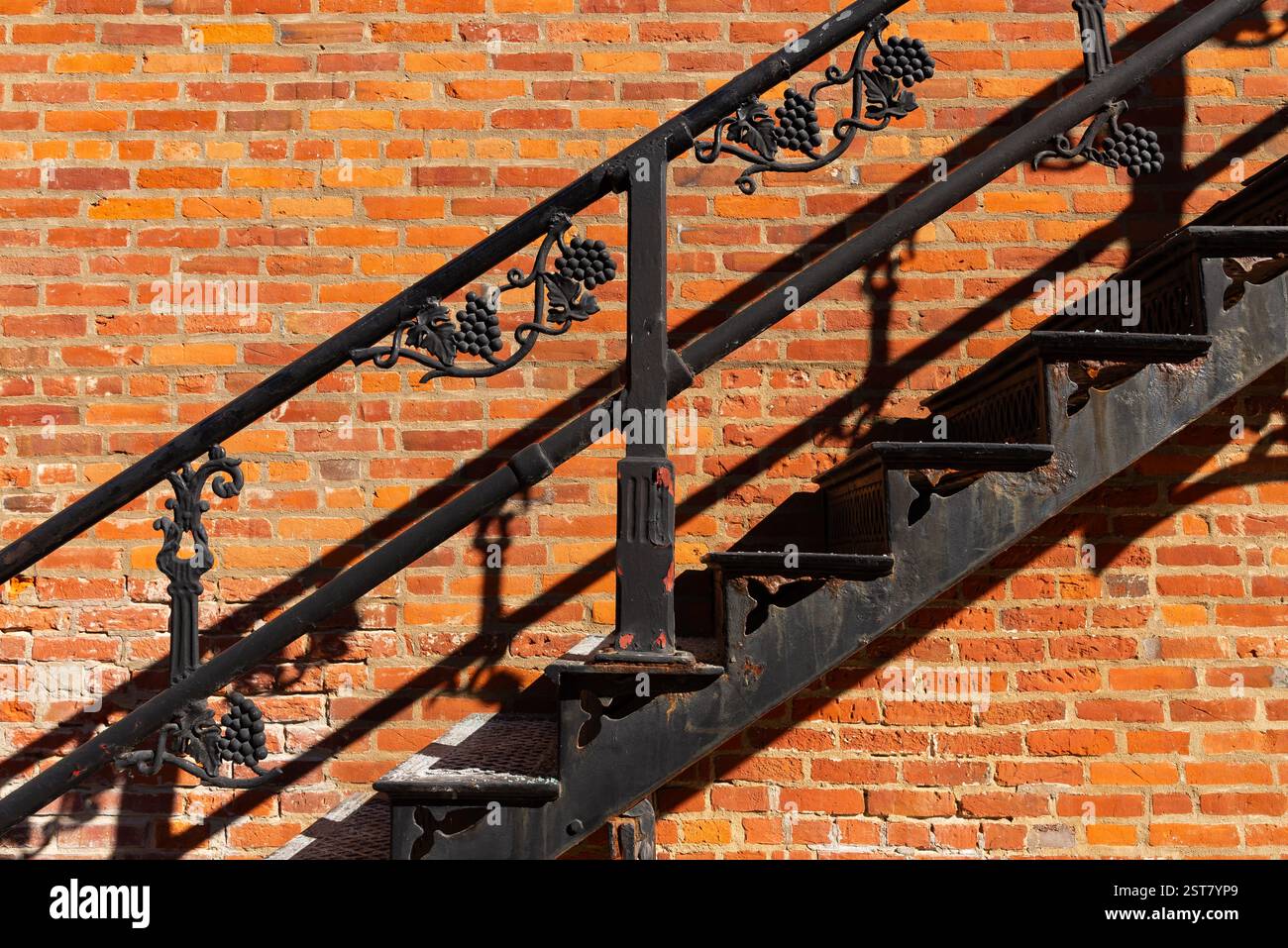 Scala in metallo nero con sfondo in mattoni rossi. Foto Stock