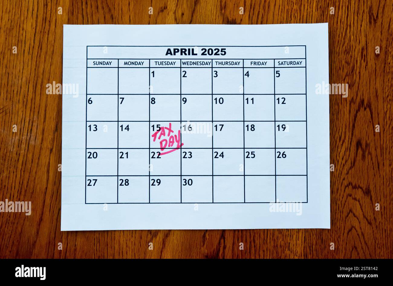 Calendario di aprile 2025 che mostra il giorno delle imposte degli Stati Uniti - 15 aprile - in lettere scritte a mano rosse sedute su un tavolo di legno. Foto Stock