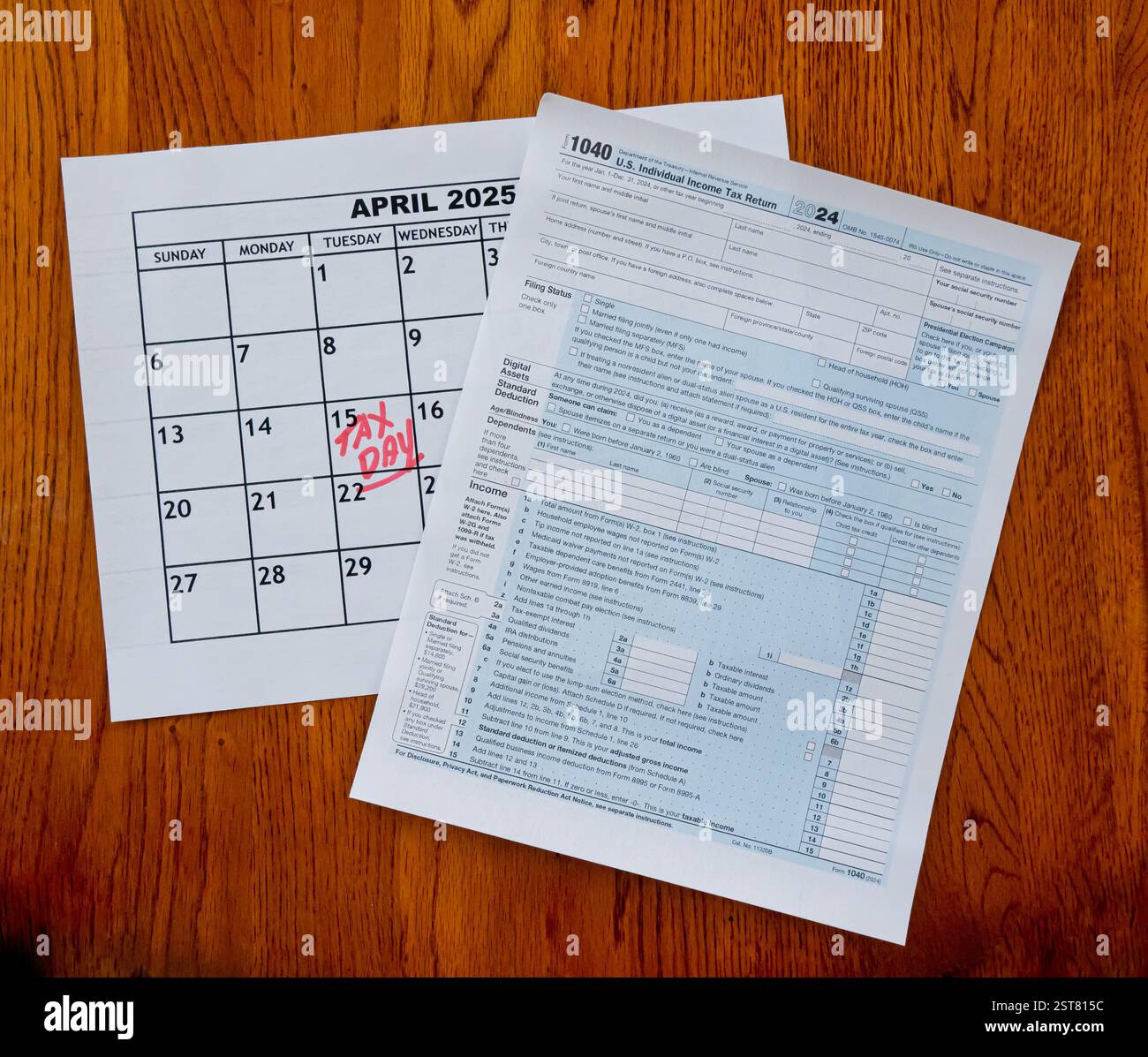 Calendario 2025 aprile giorno fiscale - 15 aprile - in lettere rosse scritte a mano e modulo IRS 1040 seduti su una scrivania di legno Foto Stock