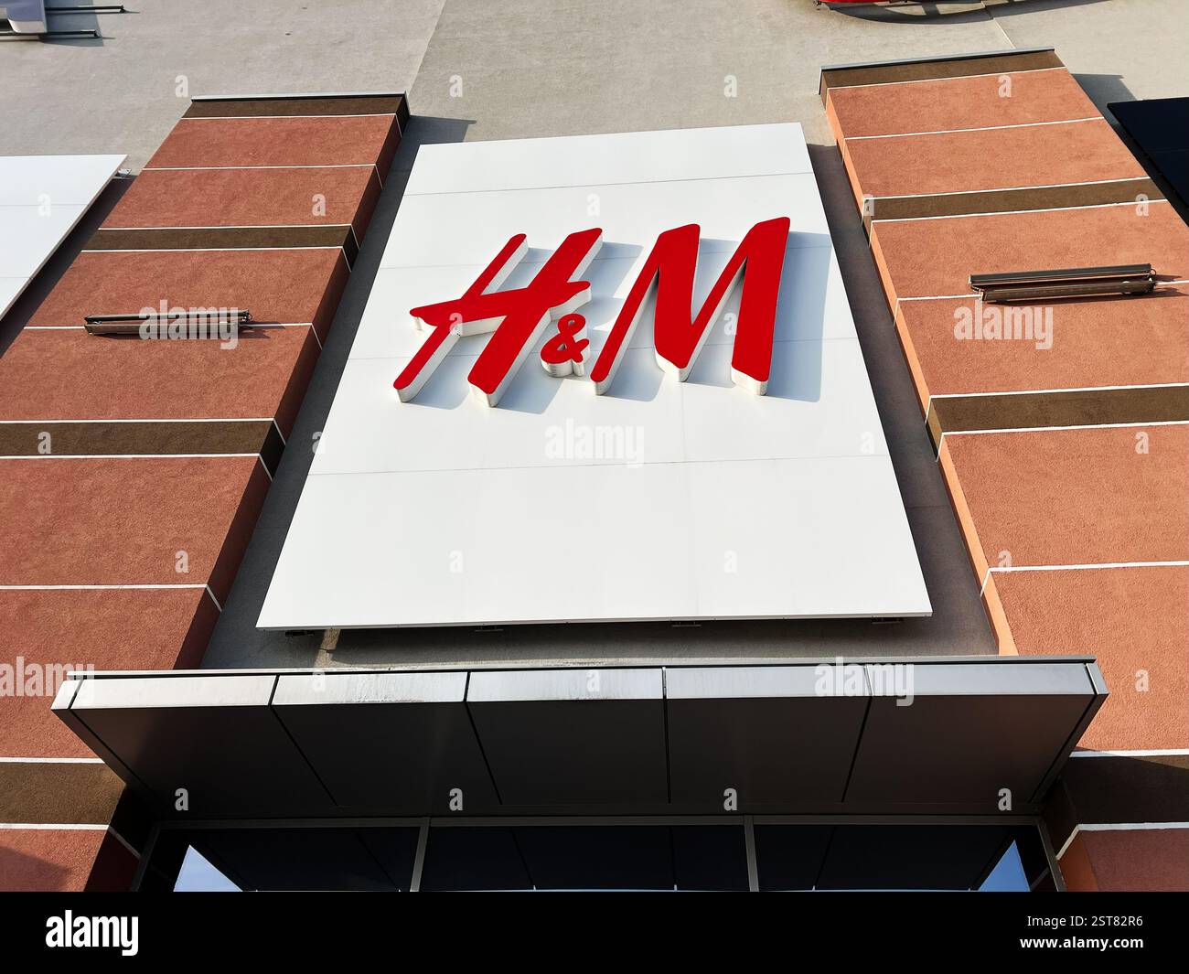 Leopoli, Ucraina - 16 febbraio 2025: Logo H e M di colore rosso su un pannello bianco montato su una facciata esterna marrone dell'edificio. Foto Stock