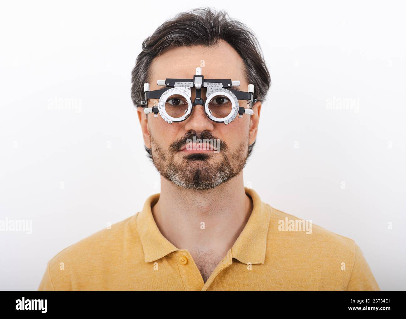 Uomo di mezza età che indossa una montatura di prova optometrista per scegliere gli occhiali per il trattamento della vista, isolata su bianco. Oftalmologia Foto Stock
