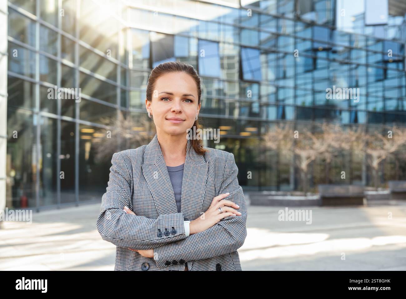 Ritratto di una donna d'affari che indossa una giacca in piedi sulla strada della città con le braccia incrociate Foto Stock