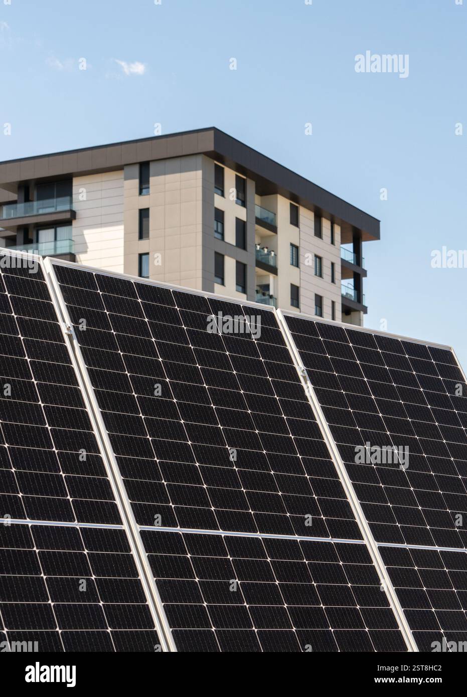 Grande pannello solare con casa residenziale in città sullo sfondo. Concetto di energia sostenibile. Foto Stock