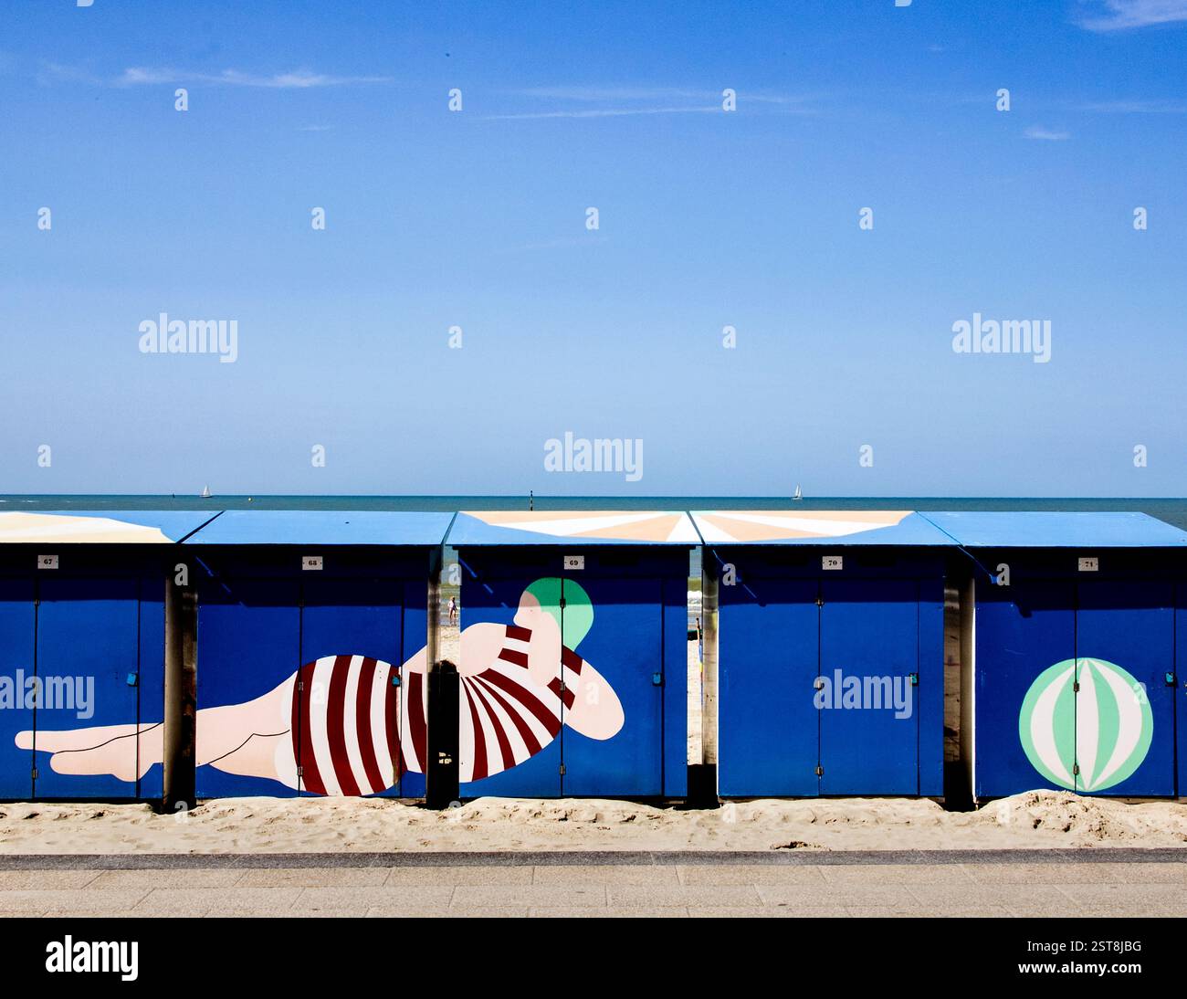 Le classiche capanne sulla spiaggia dipinte in tonalità vivaci invitano i visitatori a godersi i piaceri semplici della vita costiera. Foto Stock