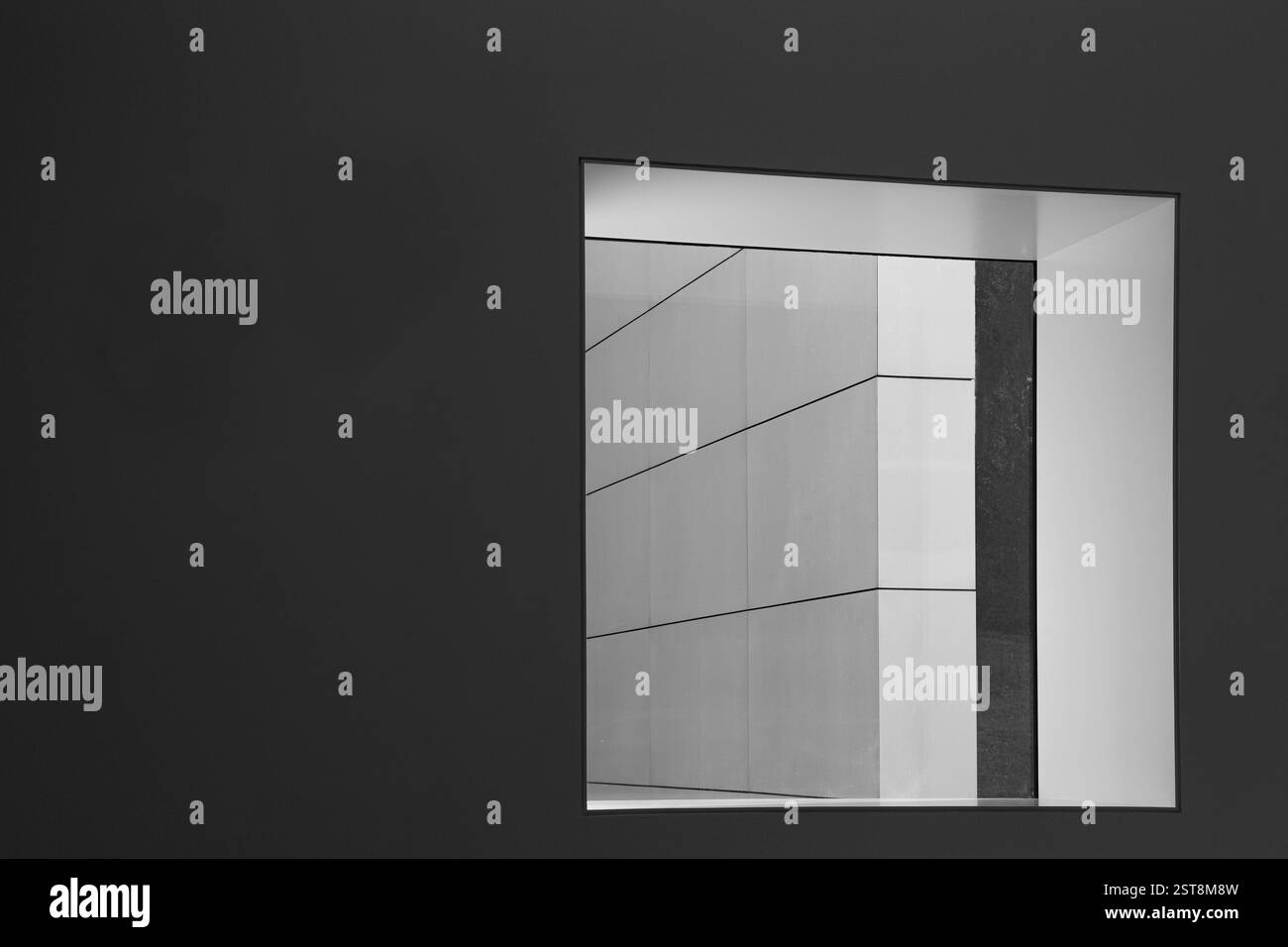 Una parete grigio scuro con una finestra che conduce ad una parete bianca con linee diagonali, edificio moderno con elementi chiari e strutturati - spazio di copia Foto Stock