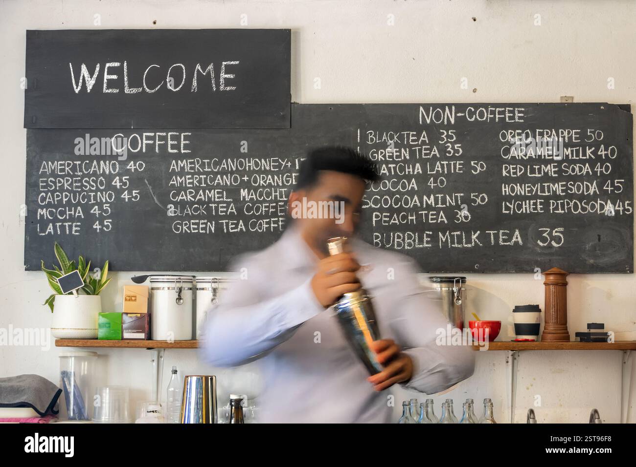 Un barista sfocato in movimento mescola una bevanda in uno shaker Foto Stock