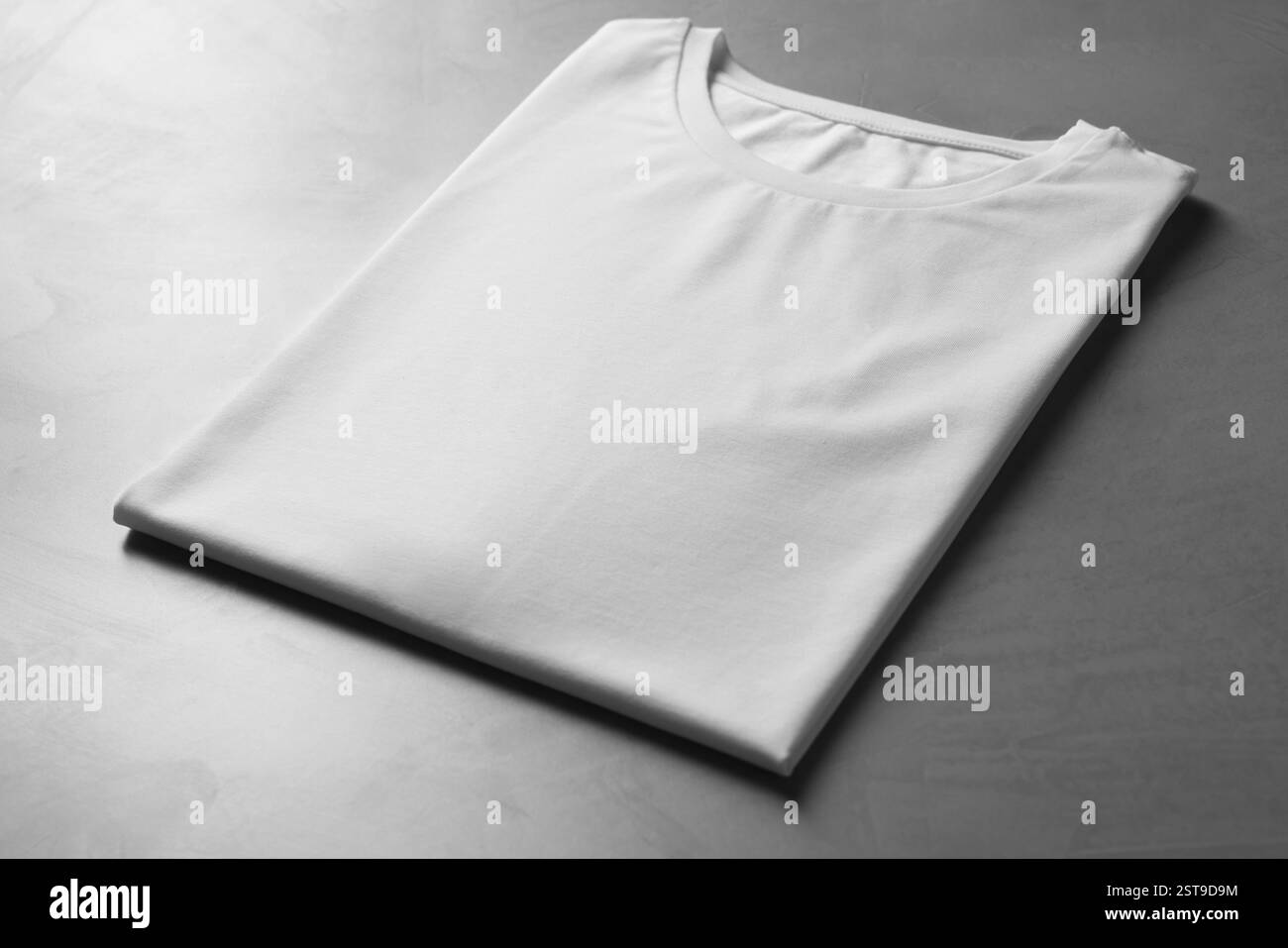 T-shirt bianca vuota sul tavolo grigio, primo piano. Mockup per il design Foto Stock