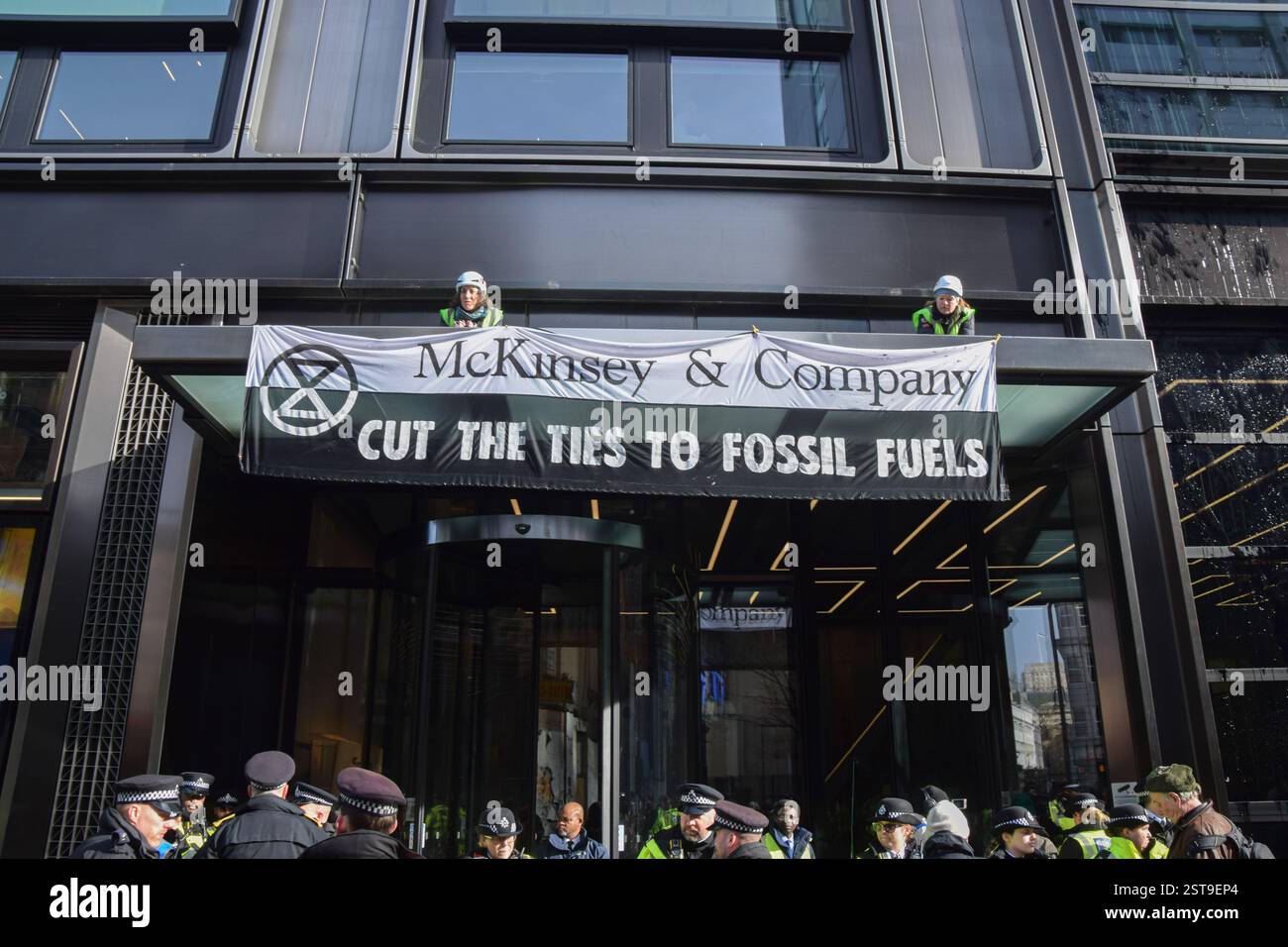 Londra, Regno Unito. 17 febbraio 2025. I manifestanti si arrampicano con uno striscione fuori dagli uffici della McKinsey and Company nel centro di Londra. I manifestanti di Extinction Rebellion spruzzarono gli uffici della società di consulenza con vernice nera e scalarono l'ingresso, invitando l'azienda a tagliare i legami con i combustibili fossili. Credito: SOPA Images Limited/Alamy Live News Foto Stock