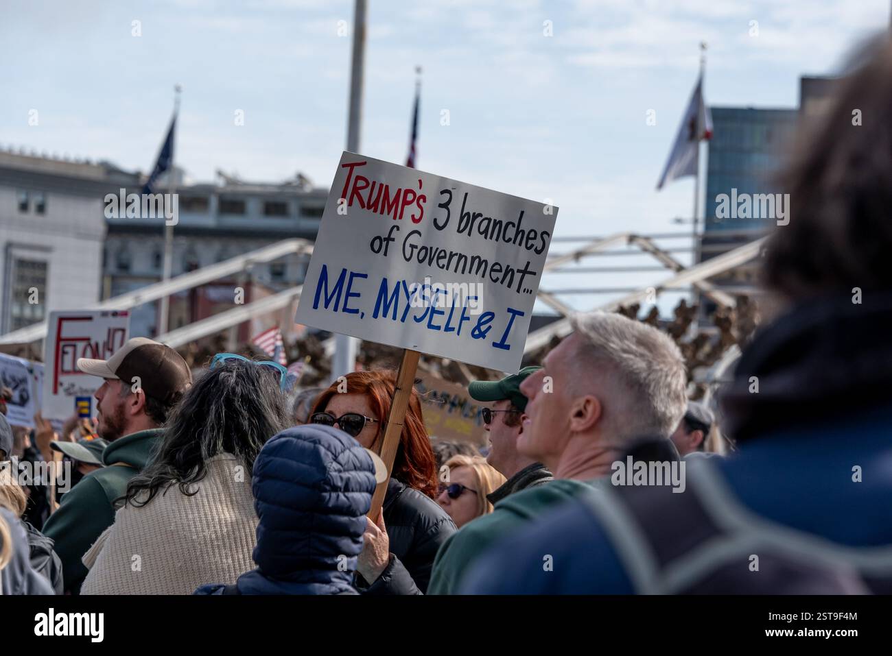 San Francisco, California, Stati Uniti, 17 febbraio 2025. Centinaia di manifestanti si riuniscono fuori dal municipio di San Francisco per una protesta del Presidents Day contro le nuove politiche e gli ordini esecutivi dell'amministrazione Trump. Un uomo ha un cartello con scritto "i tre rami del governo di Trump... Io, me e io' Shelly Rivoli/Alamy Foto Stock