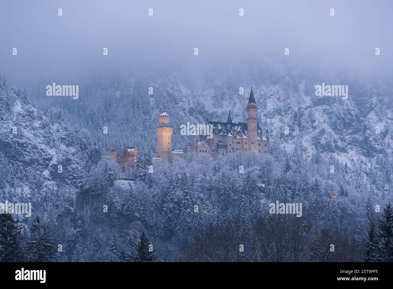 Un romantico castello brilla al crepuscolo, circondato da un paesaggio invernale innevato, illuminato, Neuschwanstein, Schwangau, Ostallgaeu, Allgaeu, Svevia Foto Stock