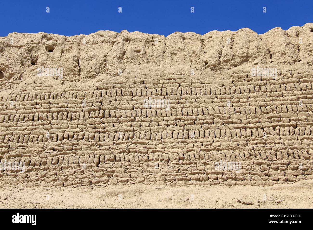 Un muro fatto di mattoni di fango. Il muro è stato eroso in alcuni punti a causa della pioggia. Foto Stock