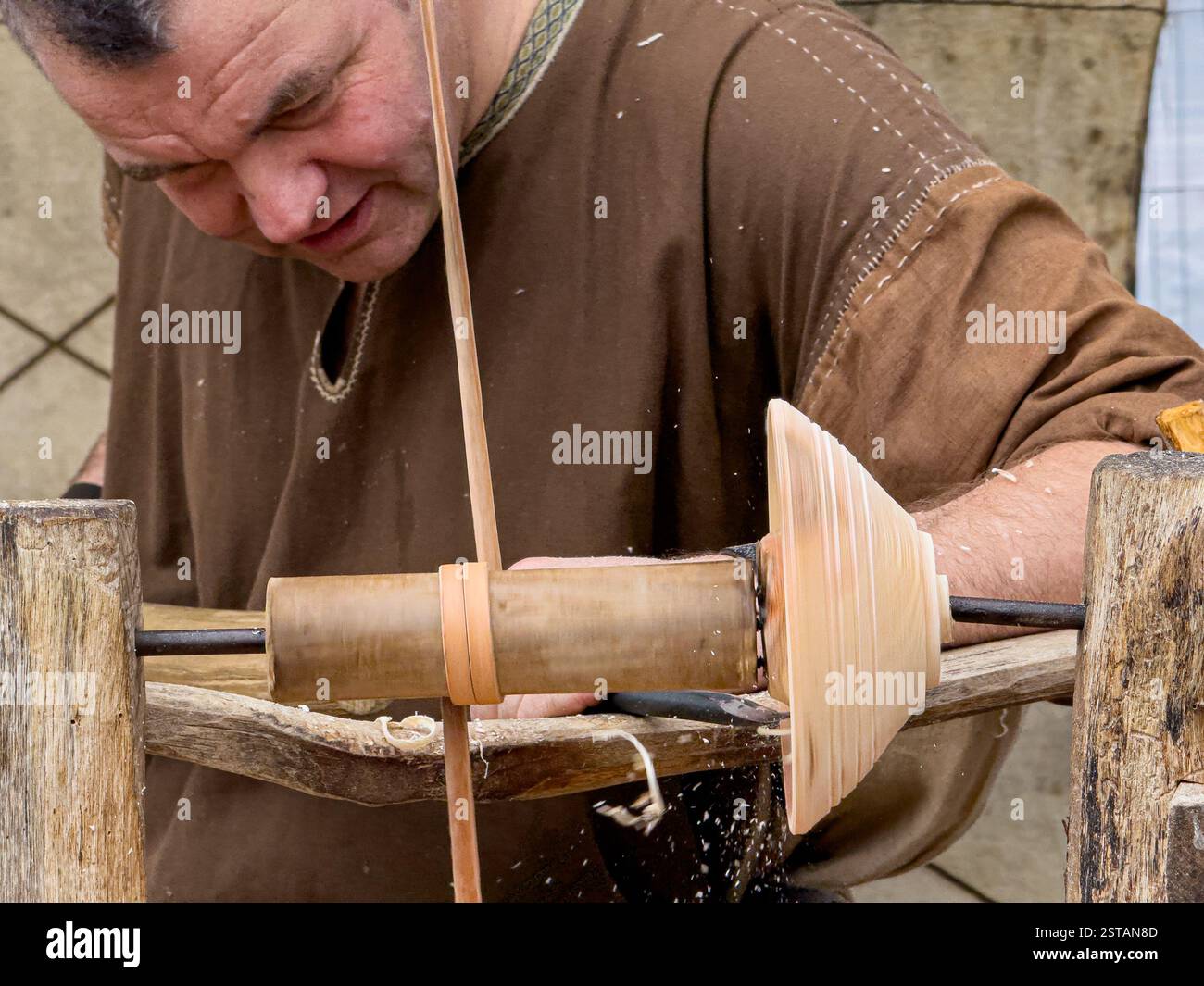 Uomo in tradizionale abbigliamento vichingo che realizza una ciotola di legno su un tornio vichingo Foto Stock