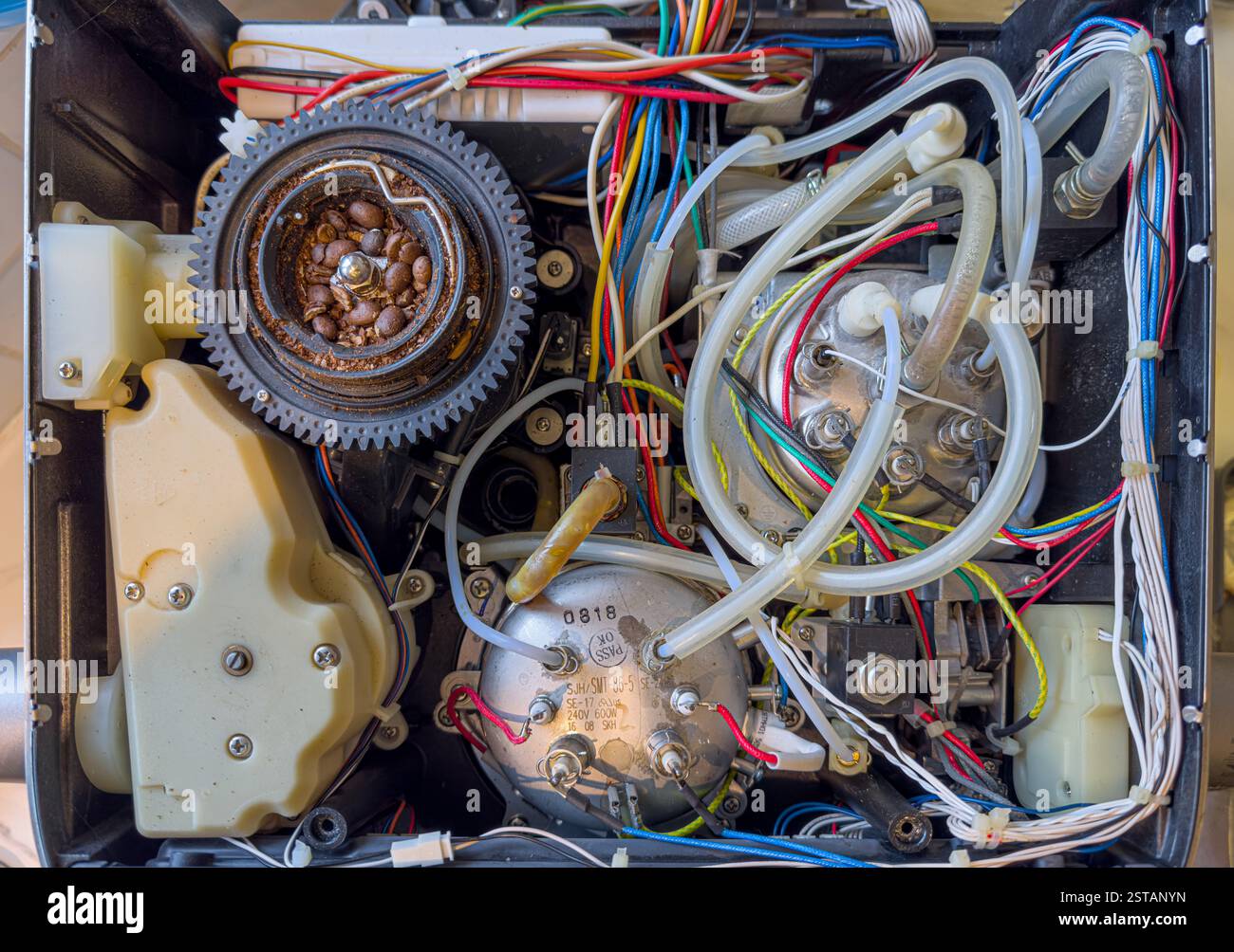Vista dall'alto verso il basso dell'interno di una macchina da caffè con macinacaffè, che rivela una complessa gamma di fili colorati, componenti e il macinacaffè esposto Foto Stock