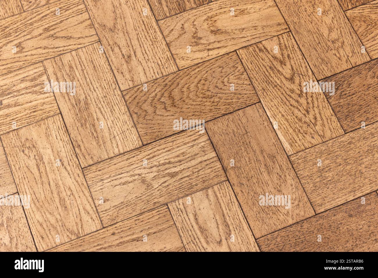 Vista ravvicinata di un pavimento in parquet in legno, con materiali naturali ed eleganza artigianale. Tonalità calde e texture dettagliate creano uno stile Foto Stock