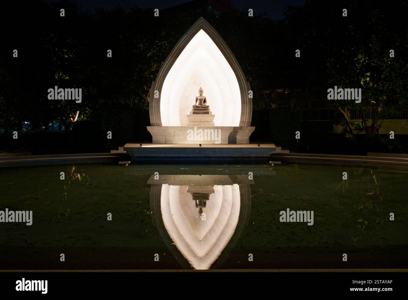Buddha seduto illuminato con riflessi d'acqua Foto Stock