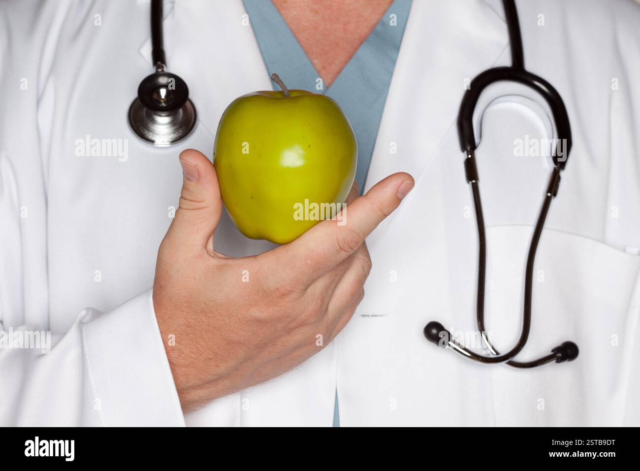 Medico maschio con stetoscopio che tiene la mela verde. Foto Stock