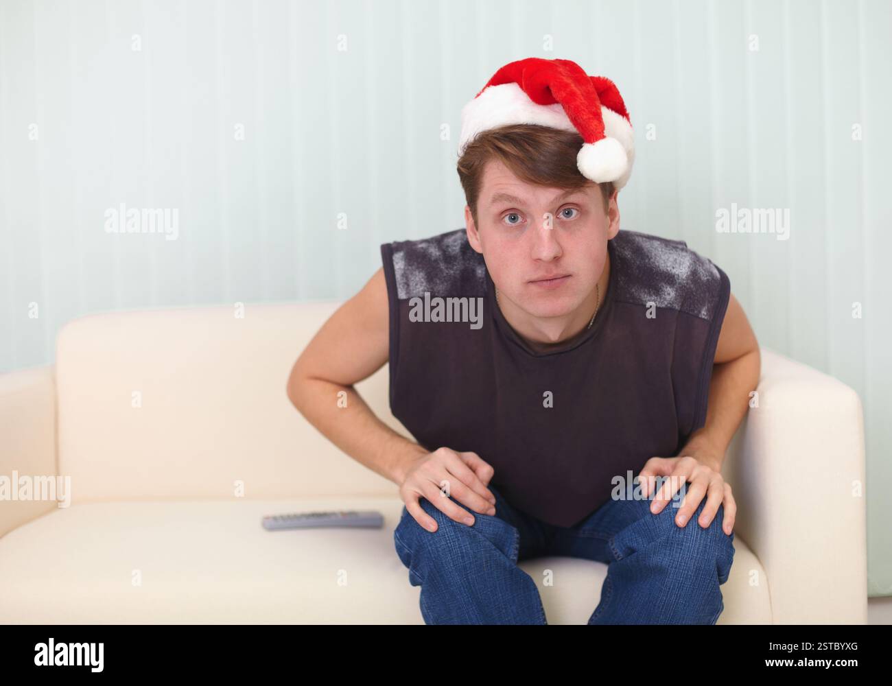 La persona con il berretto natalizio si siede sul divano e guarda la TV Foto Stock