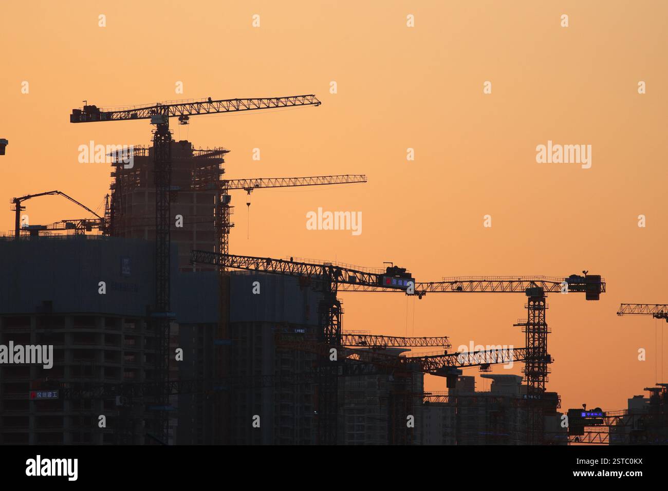 Cantiere al tramonto, gru sagomate, Shenzhen, Guangdong, Cina - febbraio 2025 concetti: Economia, rallentamento Foto Stock