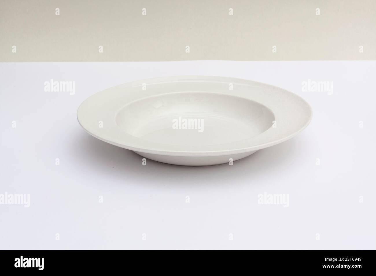 Foto minimalista di un piatto bianco vuoto su uno sfondo neutro, che mostra semplicità ed eleganza. Foto Stock