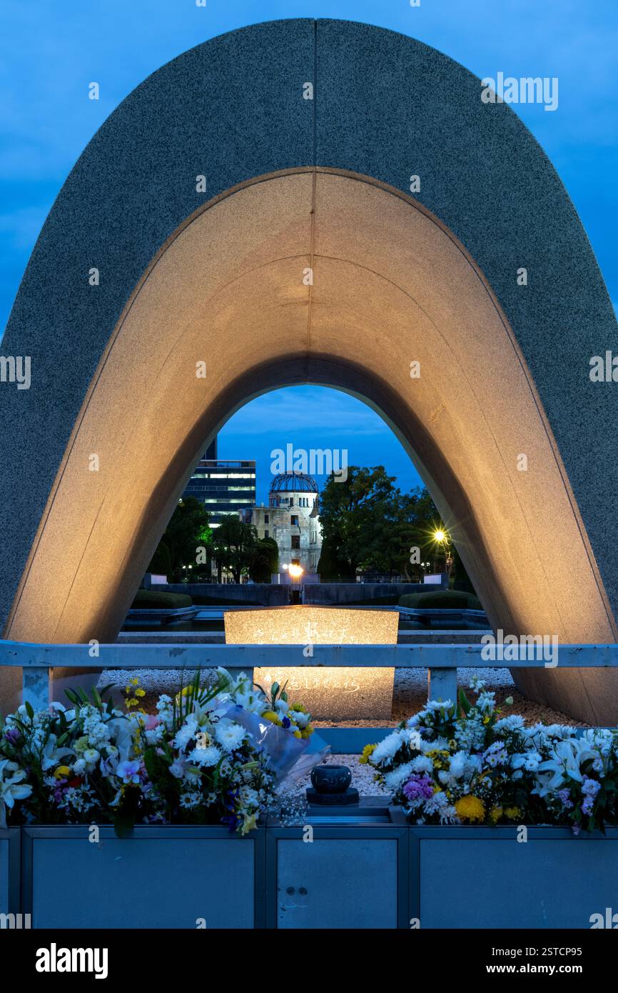 Cenotaph Memorial alle vittime di bombe atomiche nel Parco della Pace di Hiroshima, con l'Atomic Dome alle spalle, Giappone Foto Stock
