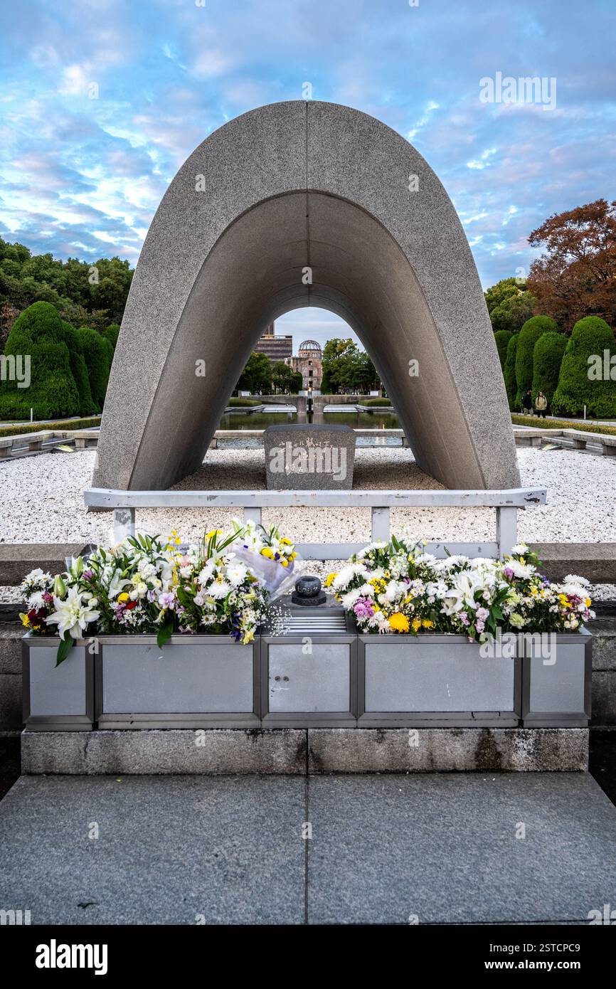 Cenotaph Memorial alle vittime di bombe atomiche nel Parco della Pace di Hiroshima, con l'Atomic Dome alle spalle, Giappone Foto Stock