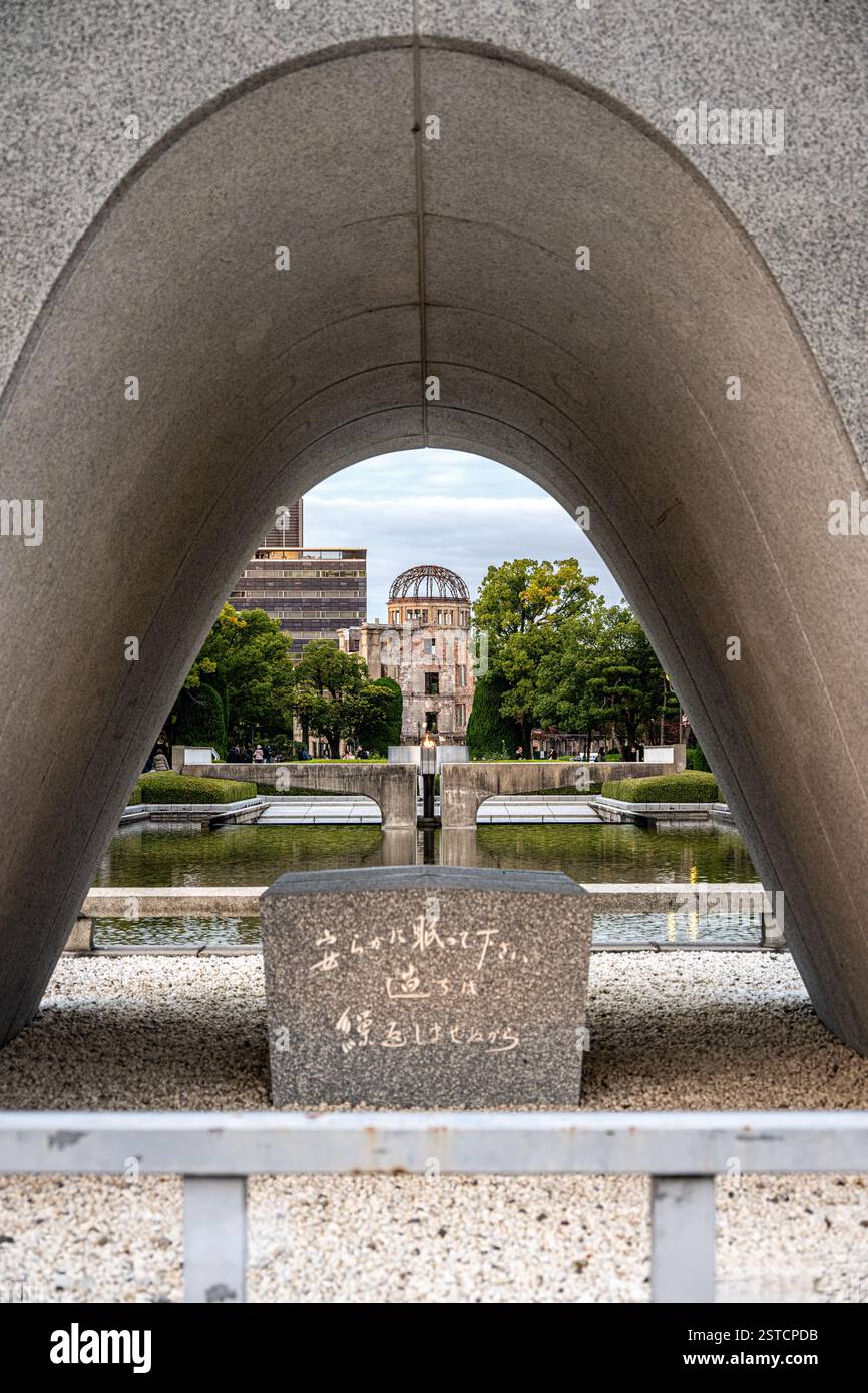 Cenotaph Memorial alle vittime di bombe atomiche nel Parco della Pace di Hiroshima, con l'Atomic Dome alle spalle, Giappone Foto Stock