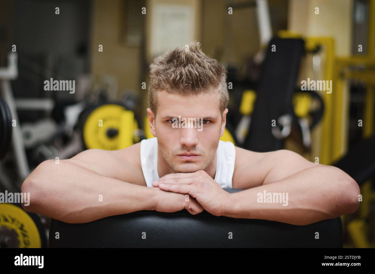 Giovane atleta attraente che riposa sulle attrezzature da palestra Foto Stock