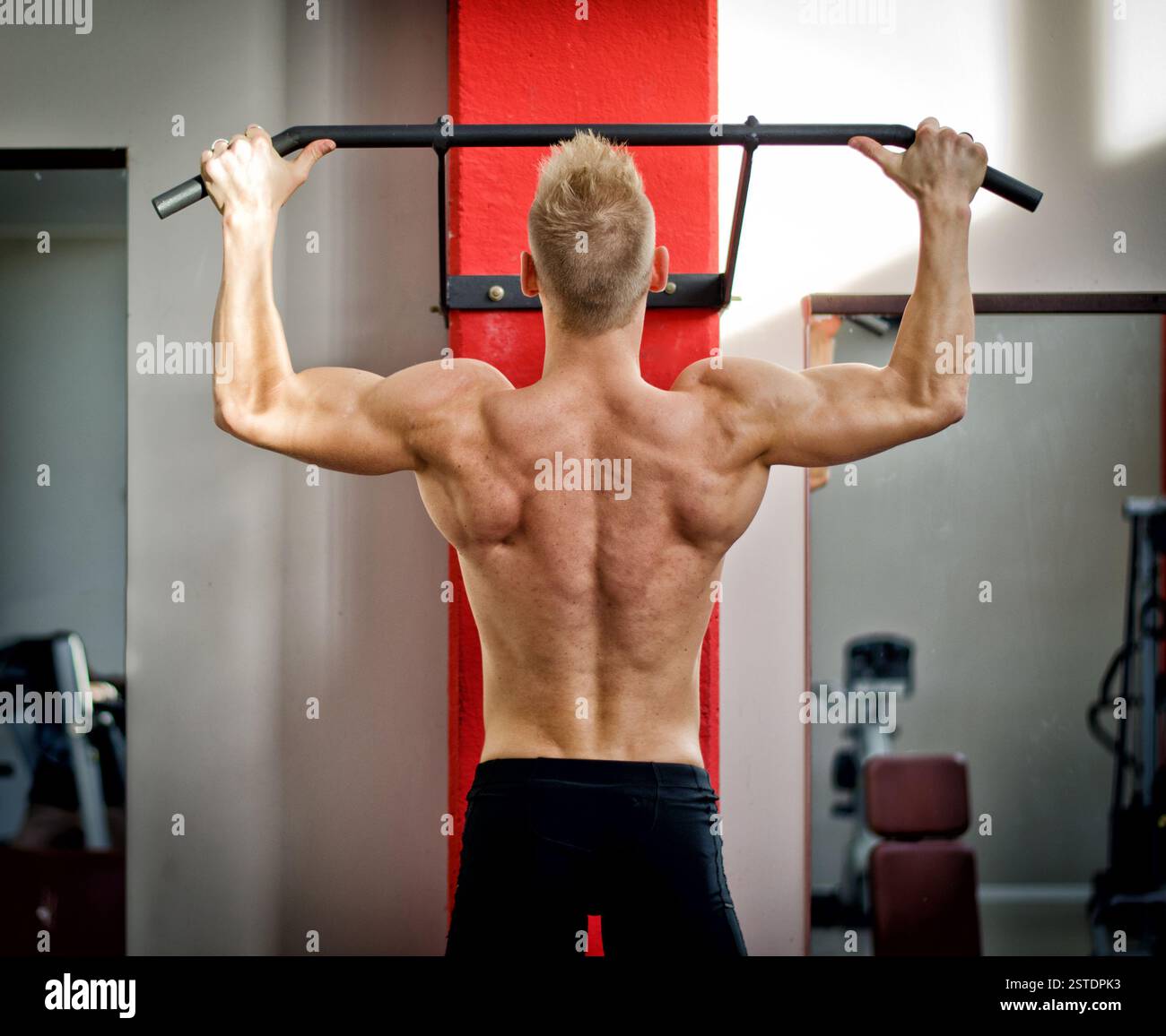 Giovane atletico appeso alle attrezzature da palestra Foto Stock