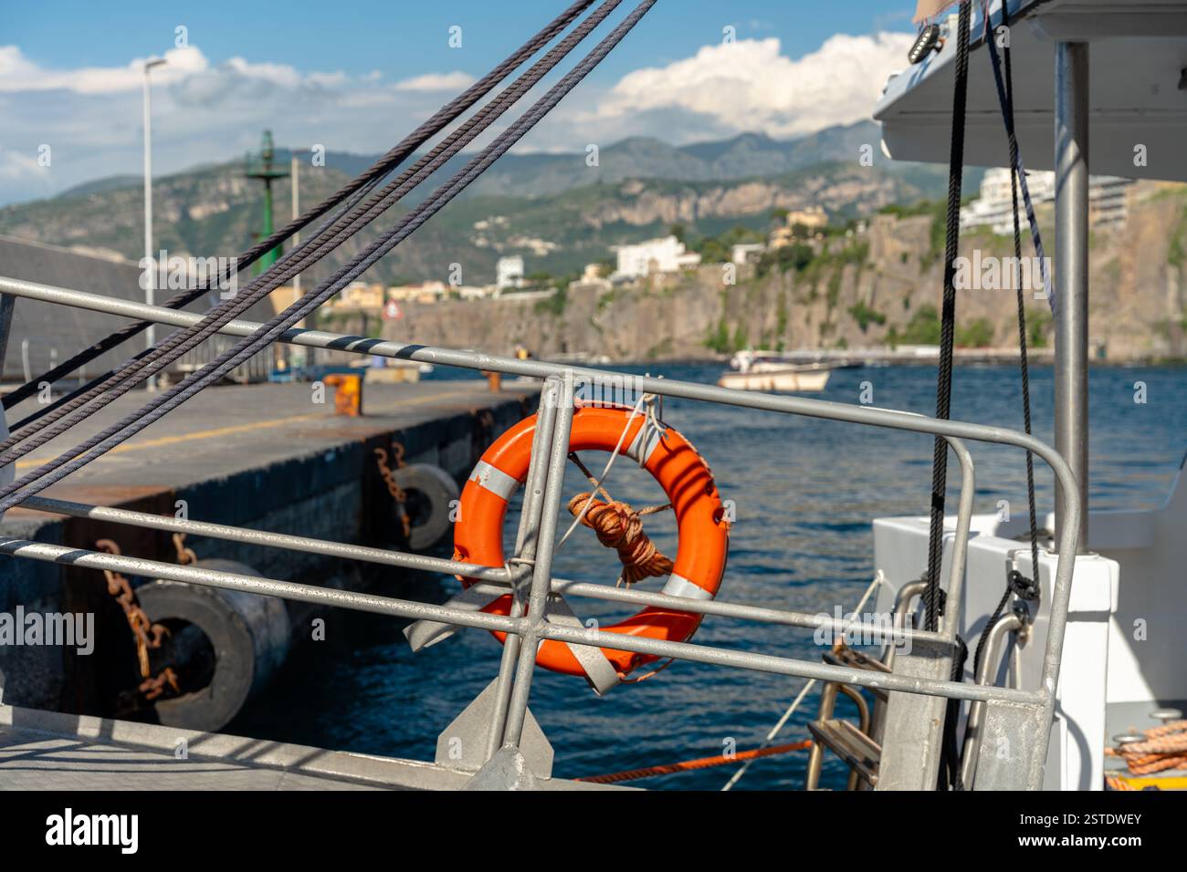Sorrento, Italia - 26 maggio 2024: Un salvagente appeso su un molo del porto di Sorrento, con le calme acque del Mar Mediterraneo sullo sfondo. Foto Stock