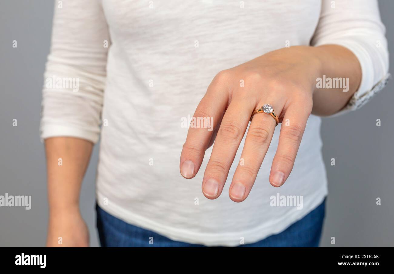 Primo piano anonimo di una mano che mostra un elegante anello di fidanzamento a diamanti, a simboleggiare l'impegno e il lusso Foto Stock
