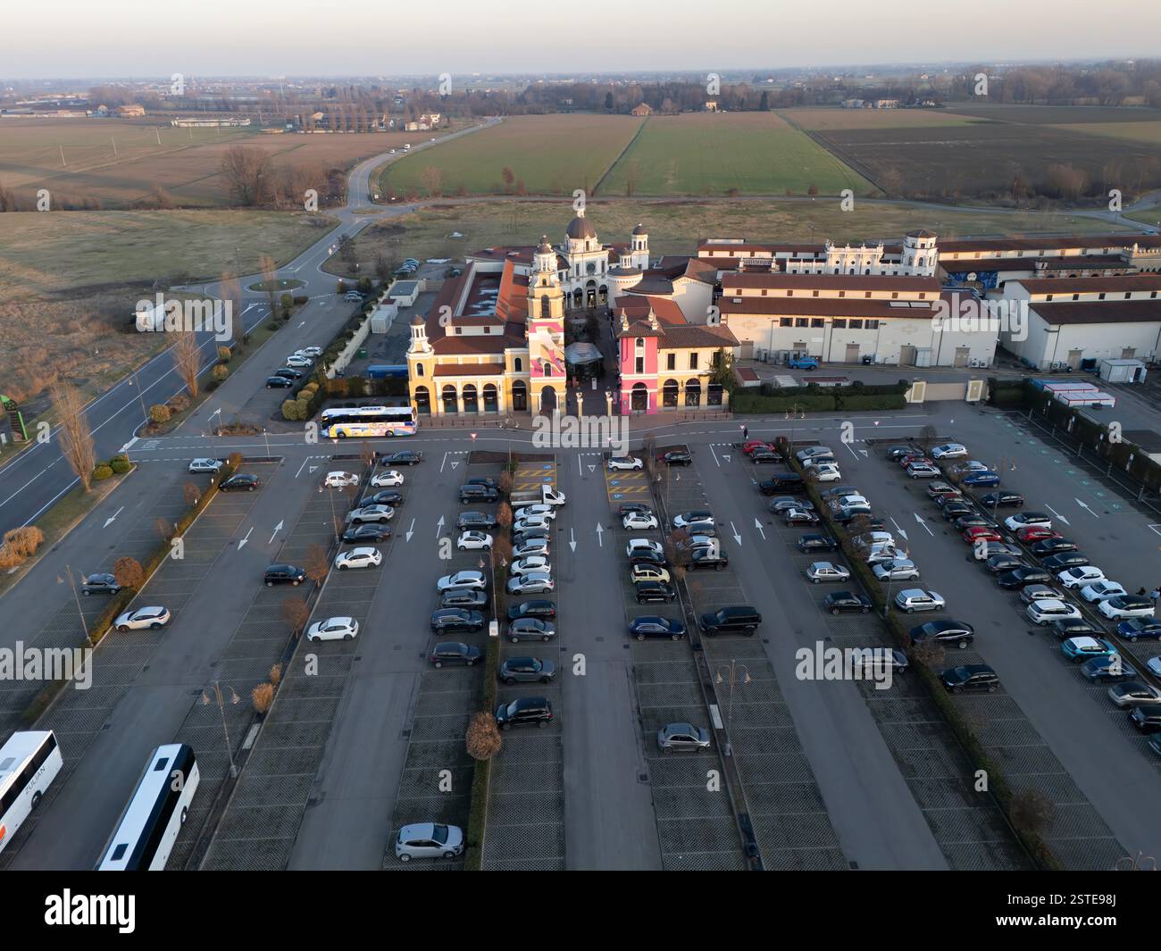Fidenza, Italia - 9 febbraio 2024 Vista aerea che cattura il centro commerciale Village con il suo ampio parcheggio, circondato da campi e strade Foto Stock